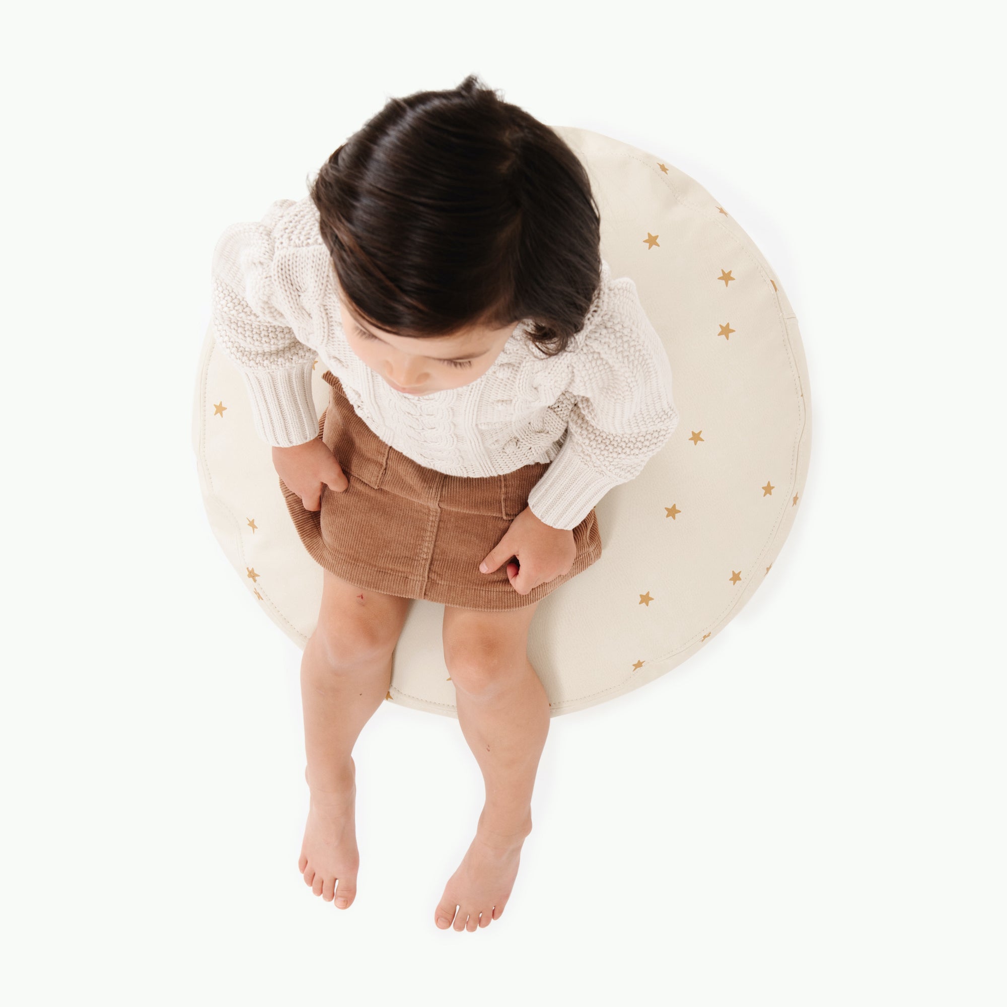 Stars (on sale)@overhead of kid sitting on the stars circle pouf