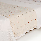Ivory@Scalloped cotton throw draped across a bed 