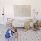 World Map@World Map Mini+ Mat hanging above a bed in a bedroom with a kid playing on the floor 