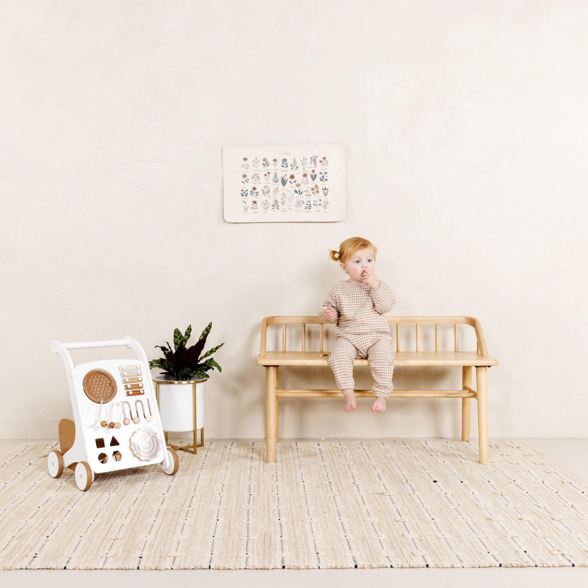 Fleurs@Baby sitting in front of Fleurs Micro mat hanging on the wall